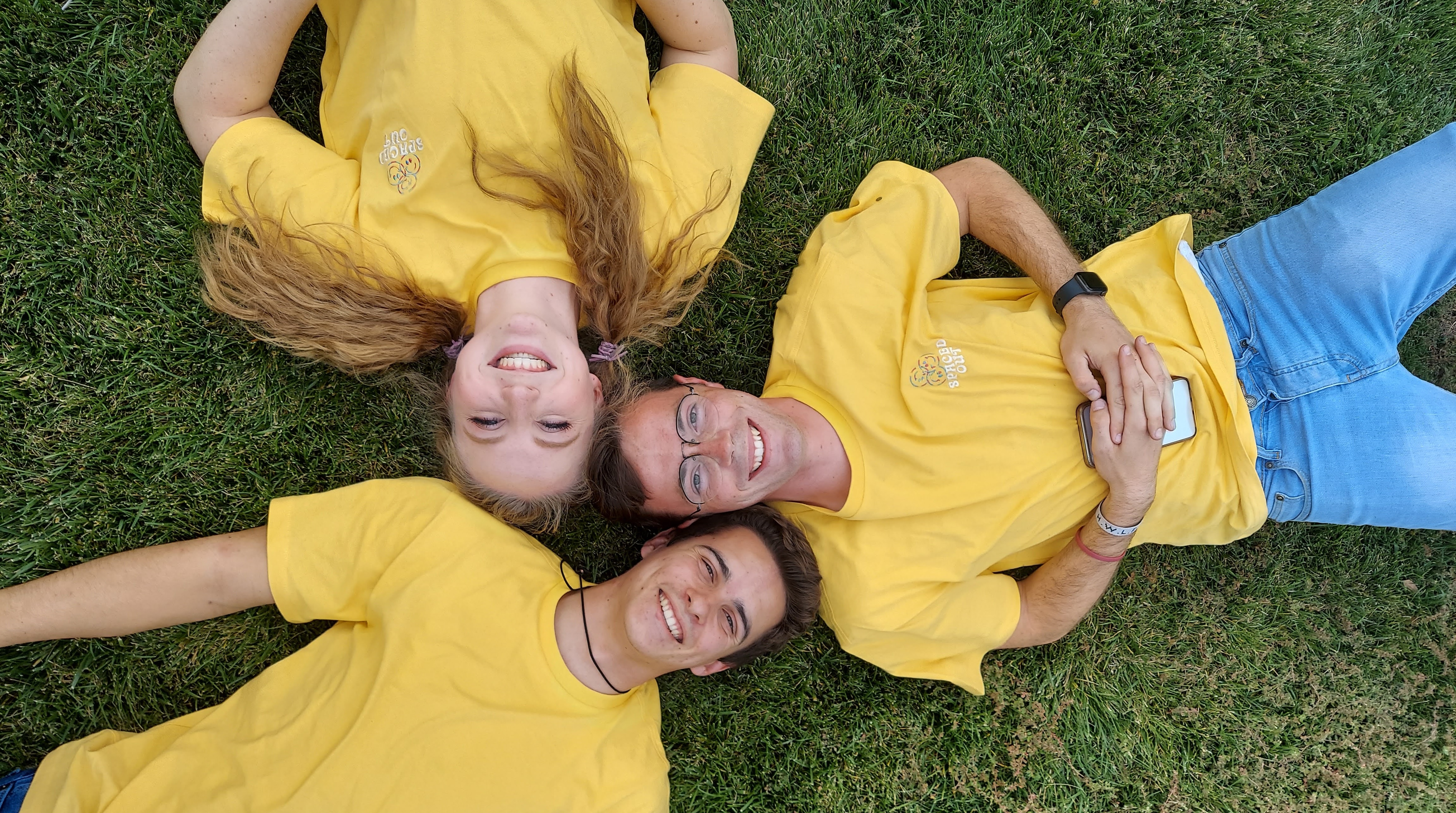 three people laying on the ground with their heads together and smiling